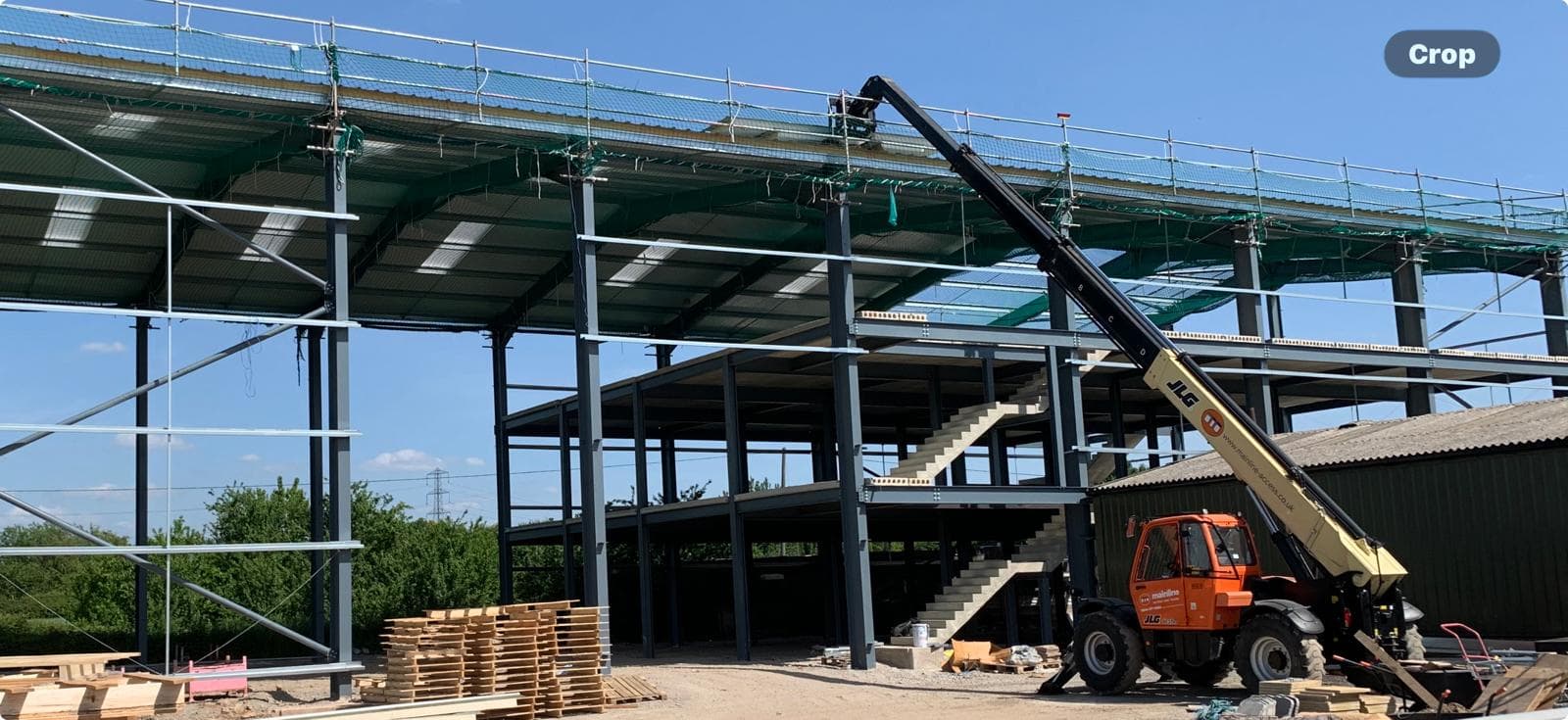 Large portal frame warehouse with internal two-storey office mezzanine during roof deck installation